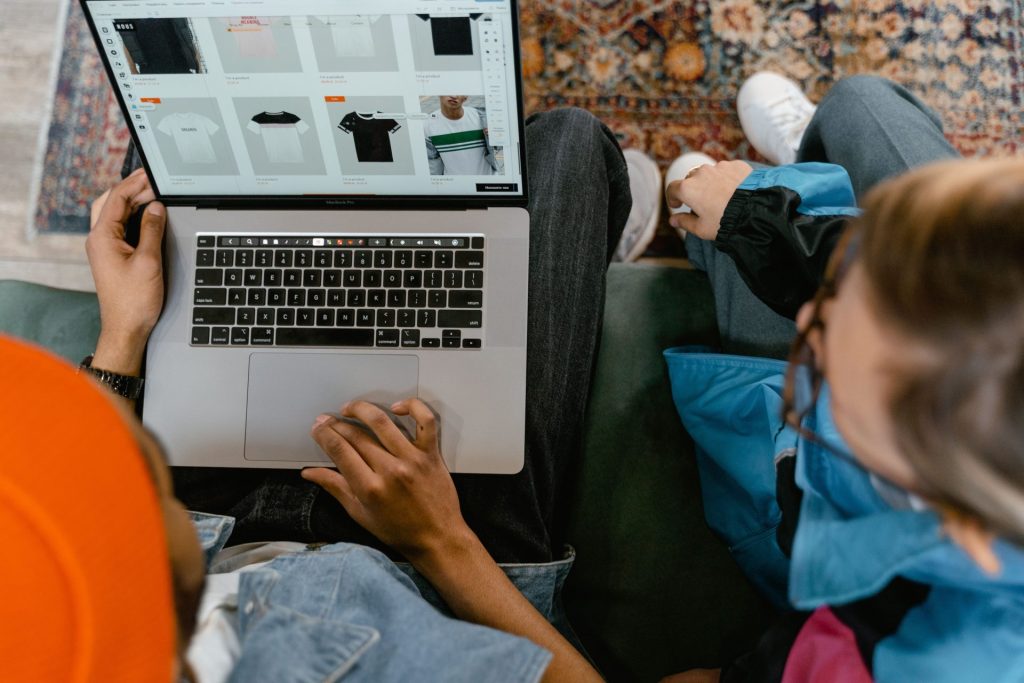 Zwei Personen betrachten von oben einen Online-Bekleidungsshop auf einem Laptop.